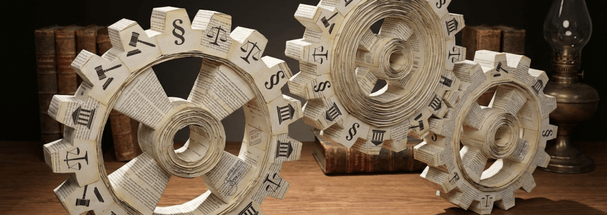 Three interlocking paper gears decorated with legal symbols on a wooden desk.
