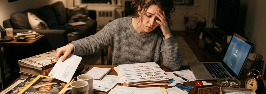 Woman overwhelmed by overdue bills and notices at a cluttered desk